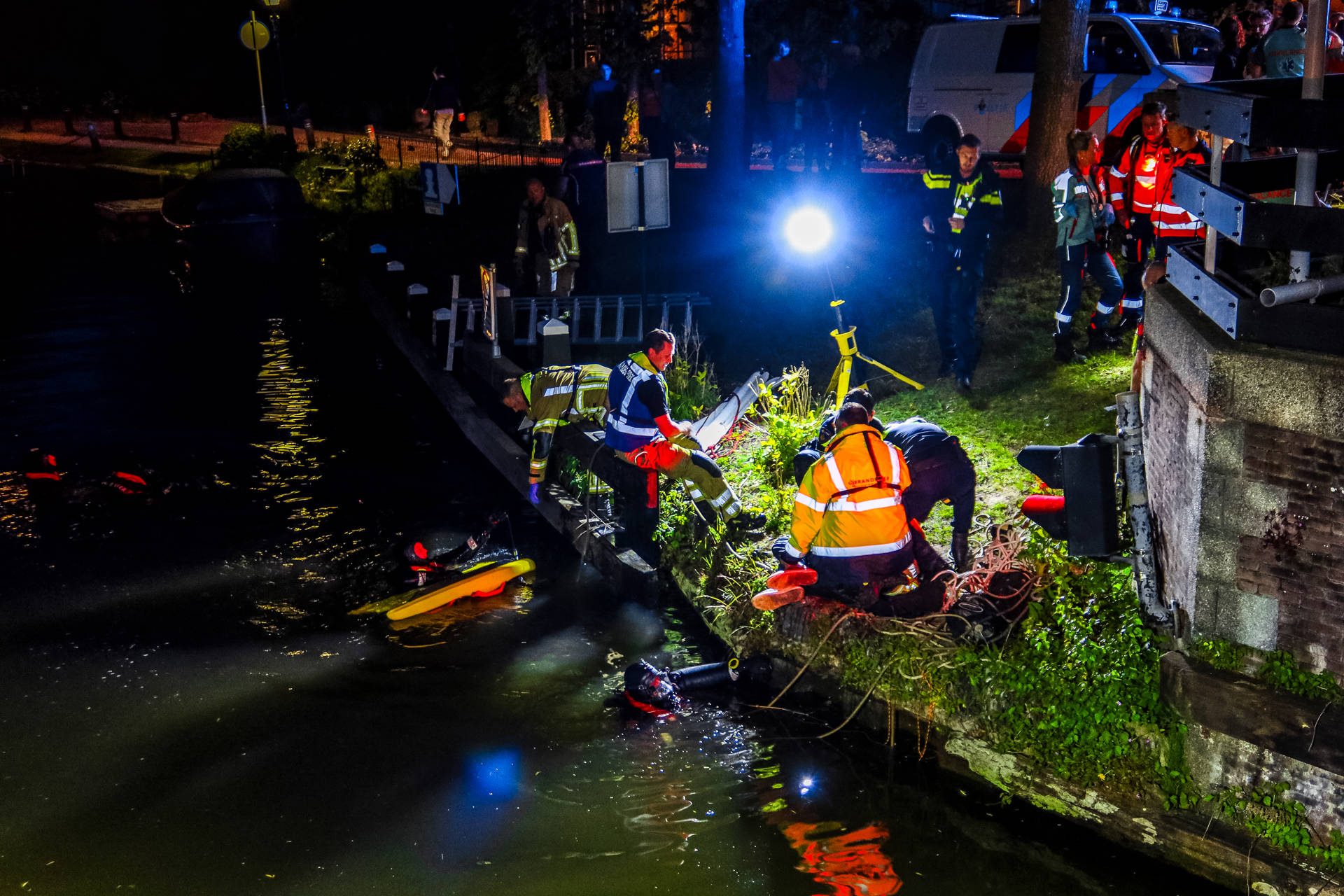 Jongeman valt in het water, omstanders schieten te hulp