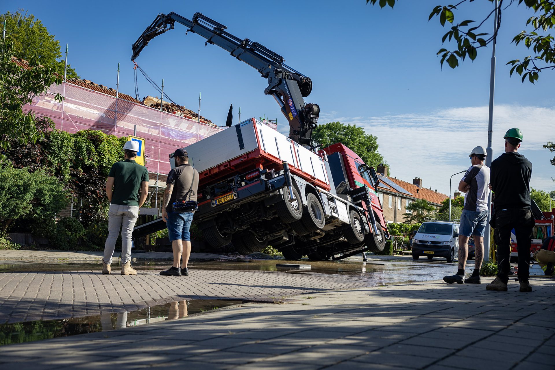 Vrachtwagen met autolaadkraan zakt door stoep